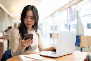 A businesswoman focuses on reading messages on her phone while working remotely at a coffee shop