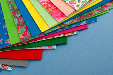 Colorful sheets of felt laid out in layers. Felt on a blue background. Sheets of felt for needlework and hobbies.