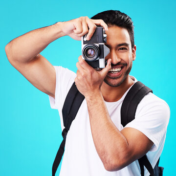 Portrait, smile and man with a camera, photography and taking picture against a blue studio background. Face, male person or model with creativity, vintage technology or photographer with inspiration