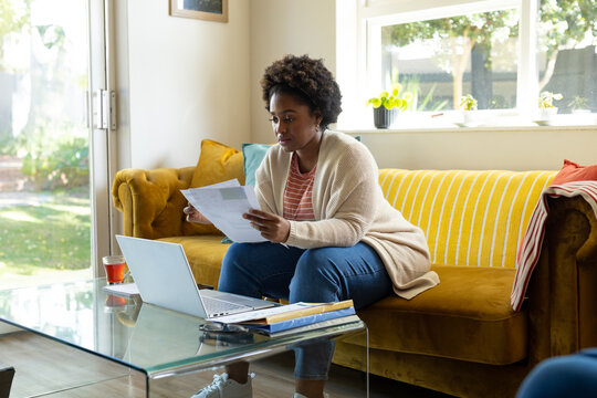 Plus Size African American Woman Doing Paperwork And Using Laptop At Home