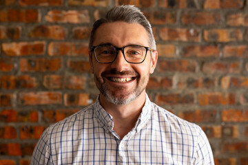 Portrait of a caucasian businessman smiling against brick wall at modern office