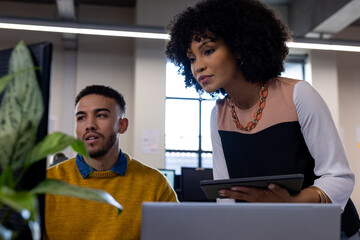 Diverse man and woman discussing over a computer at office
