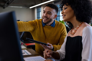 Diverse man and woman discussing over a computer at office