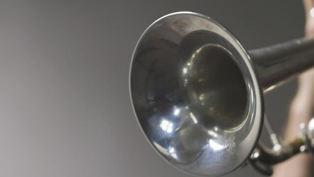 Slow motion video of a silver plated trumpet bell moving about while the instrument is being played