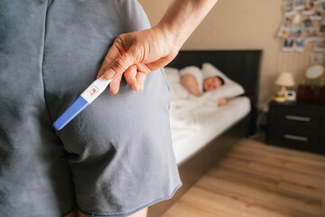 woman holding positive pregnancy test surprise for husband - obrazy, fototapety, plakaty