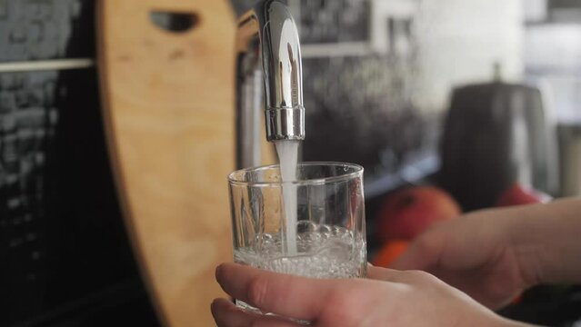 Woman pouring a tap water in glass, concept of pure drinking water.
