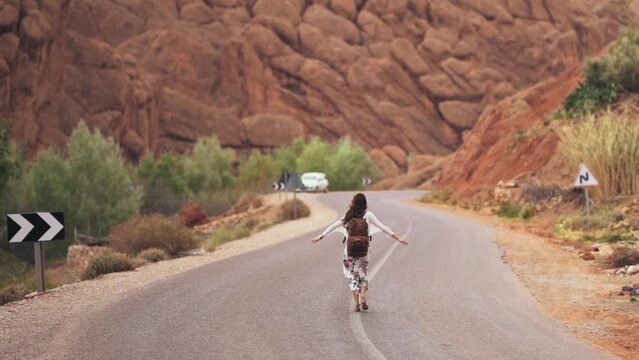 A young adventerous woman walking down the bendy road in the death valley in america on the hottest day of the year.