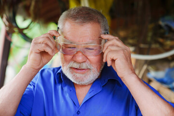 an elderly man in goggles to work with a circular saw