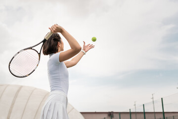 back view of female player hitting the ball while playing tennis on court, motivation and sport