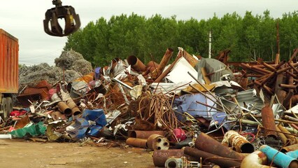 Loading scrap metal into a truck. The grab crane loads rusty metal scrap. Grab truck loads scrap industrial metal for recycling - Powered by Adobe