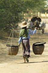 Bagan, Myanmar – January 22, 2008: Burmese man carrying two baskets on his shoulder, Bagan,...