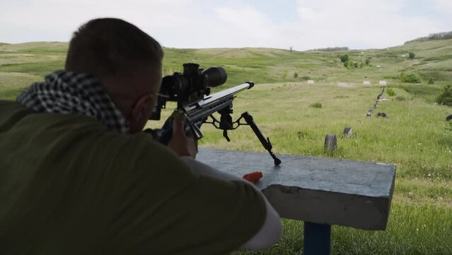 An athlete shoots a rifle with an optical sight from a prone position