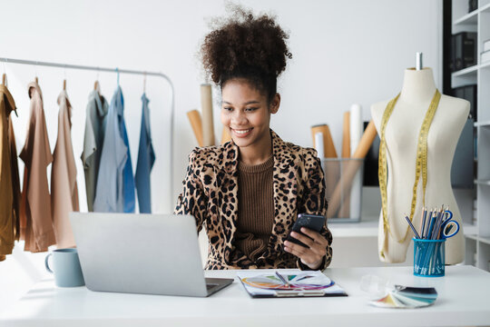 Female fashion designers use smart phones and use laptops with digital tablet computers to get orders from customers.