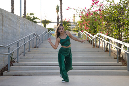 Latin and Hispanic girl, young and beautiful, dancing modern dance in the street outdoors. Dance concept, moonwalk, jumpstyle, shuffle, electrodance, hip hop, funky, popping.