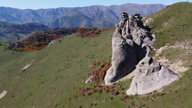 Mountain aerial flies along weathered granite outcrops on summit slope
