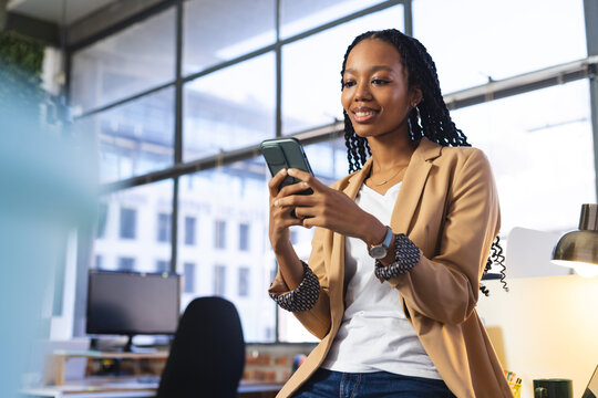 Happy african american casual businesswoman using smartphone in office