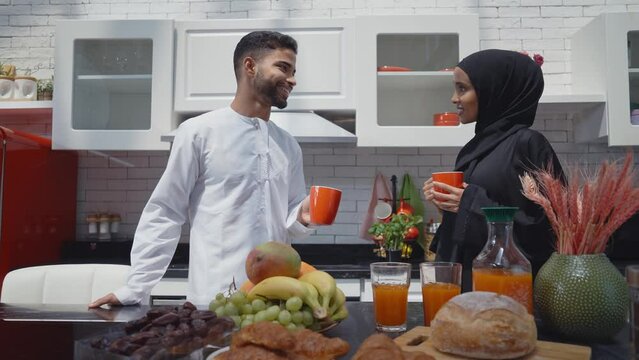 Happy couple wearing traditional outfits from the emirates spending  time in the kitchen of their beautiful modern apartment in Dubai