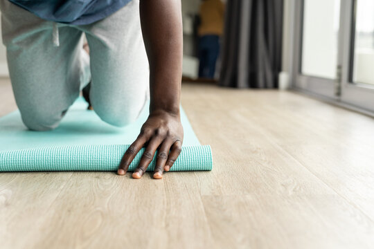 Midsection of african american man placing yoga mat on floor at home, copy space