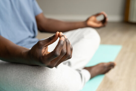 Midsection of african american man doing yoga and meditating at home