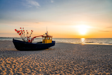 Sunset on the beach on the Polish Baltic Sea. Fishing boat in the evening near Międzyzdroje,...