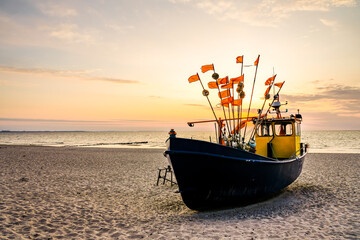 Sunset on the beach on the Polish Baltic Sea. Fishing boat in the evening near Międzyzdroje, Poland.
