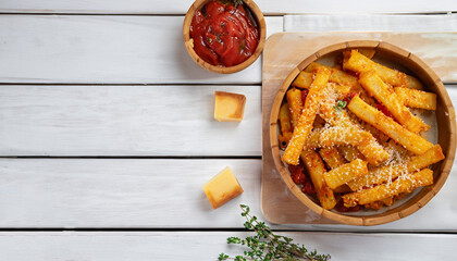 garlic parmesan polenta fries with parmesan cheese, thyme and spices in a bamboo dish with tomato...
