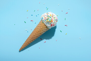 top view of ice cream cone and strewed sprinkles on blue with hard shadow, minimal  summer concept