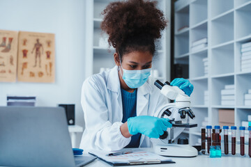 African American female technician testing blood sample in lap. blood test is one of the most...