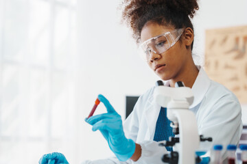 African American female technician testing blood sample in lap. blood test is one of the most...