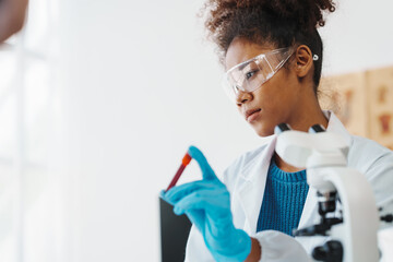 African American female technician testing blood sample in lap. blood test is one of the most...