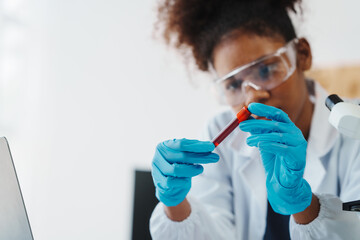 African American female technician testing blood sample in lap. blood test is one of the most...