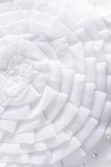 Elegant vertical background of the bride's wedding dress part. soft folds of a large white silkworm...