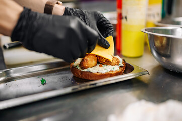 chef hand cooking cheese burger with vegetables and meat on restaurant kitchen