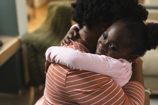 Happy african american mother and daughter embracing before school at home