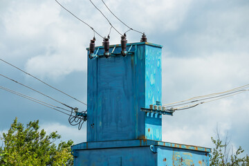 Old electrical transformer station with wires and insulators close-up on a summer sunny day