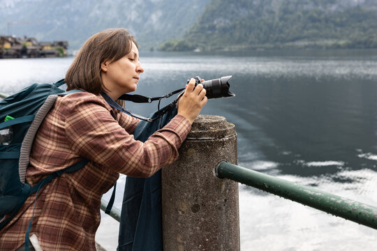 A female tourist with a backpack takes pictures of a large laker, the concept of outdoor recreation, Hallstatt, Austria