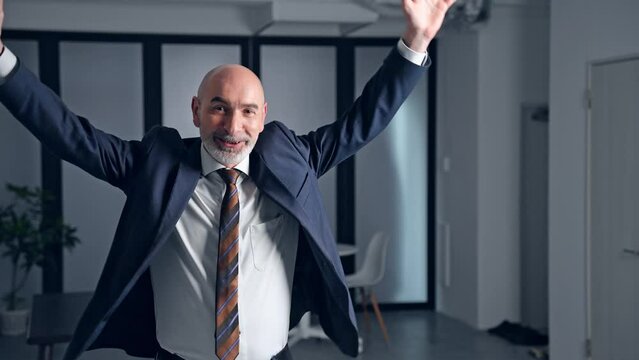 Dancing middle-aged white man in a suit in the office.