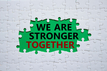 We are stronger together symbol. White puzzle with words We are stronger together. Beautiful green background. We are stronger together concept. Copy space.