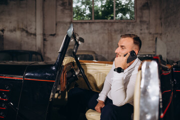 a man is talking on the phone while sitting in a retro cabriolet