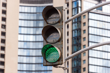 Green traffic light on the background of a multi-storey office building.