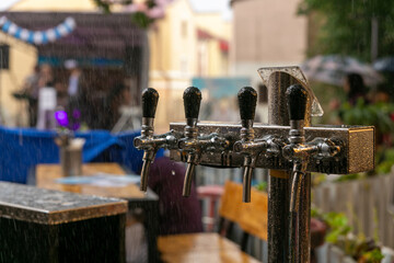 Chromed taps for draft beer in a street cafe under the rain.