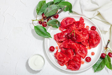 Dumplings, filled fresh cherries. Ripe fruits, sweet sauce, sour cream. Traditional Ukrainian dish