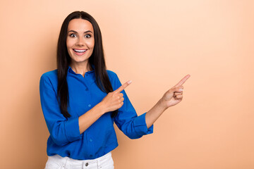 Portrait of attractive amazed lady promoter directing fingers empty space amazing sale offer news isolated beige color background