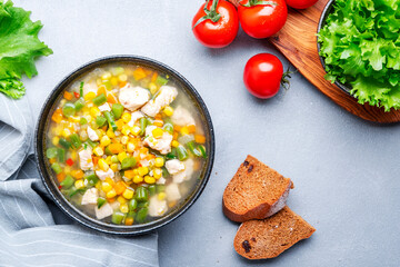 Chicken and vegetable soup with sweet corn and green beans. Comfort food. Gray table background, top view