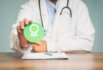 Physician holding a quality assurance symbol while sitting at the table in the hospital.