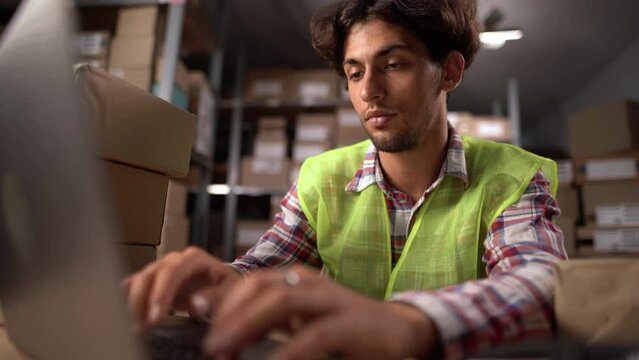 Professional male worker uses laptop checking software in the retail warehouse, POV. Close-up view