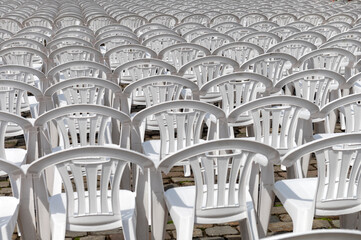 Rows and rows of white resin pvc plastic patio garden chairs. .Monotony