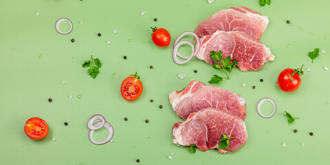 Pieces of pork meat with parsley, purple onion rings and tomato, raw fresh steaks concept