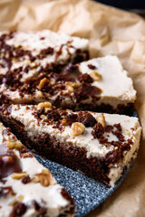 Homemade brownie chocolate cake with coffee cream and walnuts on baking paper.