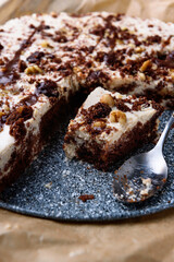 Homemade brownie chocolate cake with coffee cream and walnuts on baking paper.